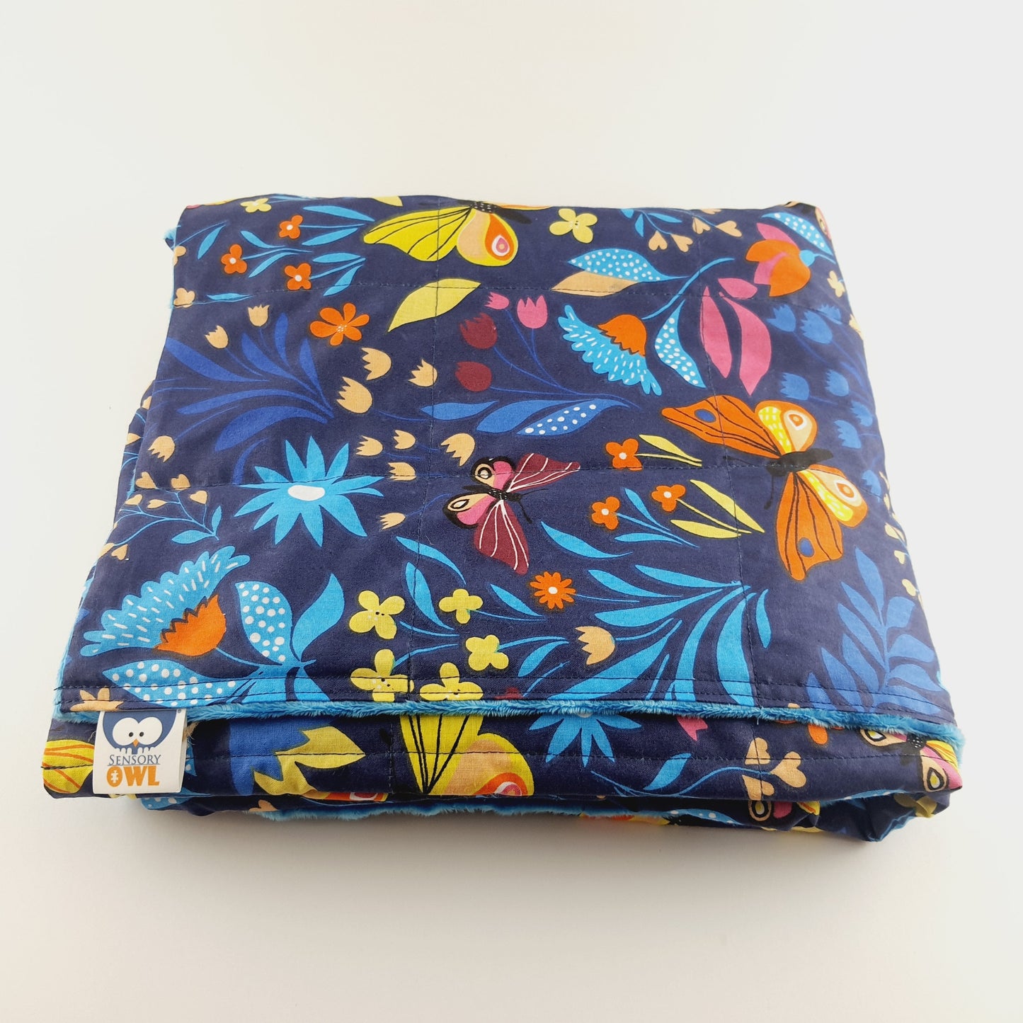 Folded fabric with colorful floral and butterfly pattern on a white background