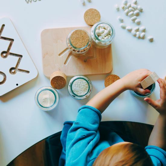 sensory learning and exercise tile presenting a child trying to pick small parts from the jar