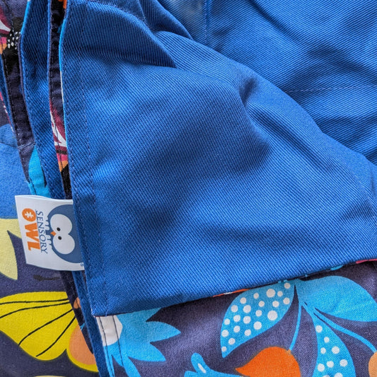 Close-up of a blue fabric with a colorful patterned border and a visible brand label.